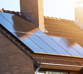 Close-up of rooftop solar panels and chimney. Residential house with solar panels on roof. Solar energy