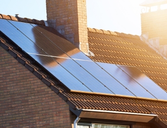 Close-up of rooftop solar panels and chimney. Residential house with solar panels on roof. Solar energy