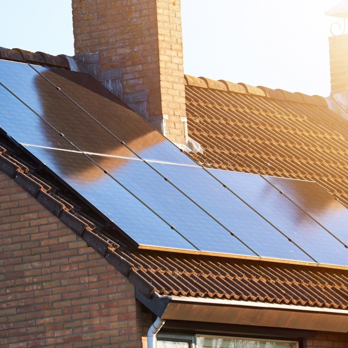 Close-up of rooftop solar panels and chimney. Residential house with solar panels on roof. Solar energy